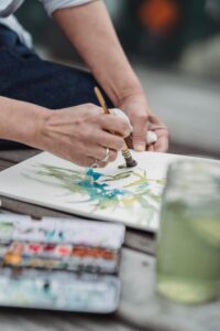 A person painting watercolors outdoors, showcasing creativity and artistic expression.